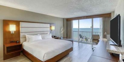 King size bed, TV screen and window in a hotel room at the DoubleTree Beach Resort by Hilton Tampa Bay - North Redingto.