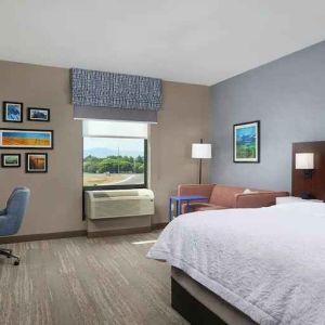 King bedroom with desk, window and sofa at the Hampton Inn Burley.