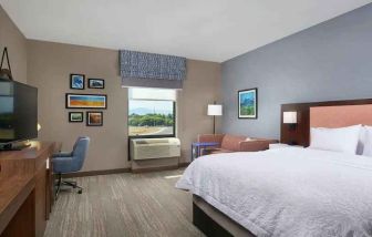 King bedroom with desk, window and sofa at the Hampton Inn Burley.