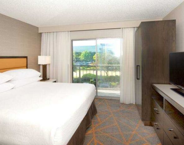 King bedroom with window and TV screen at the Embassy Suites by Hilton Cincinnati Blue Ash.