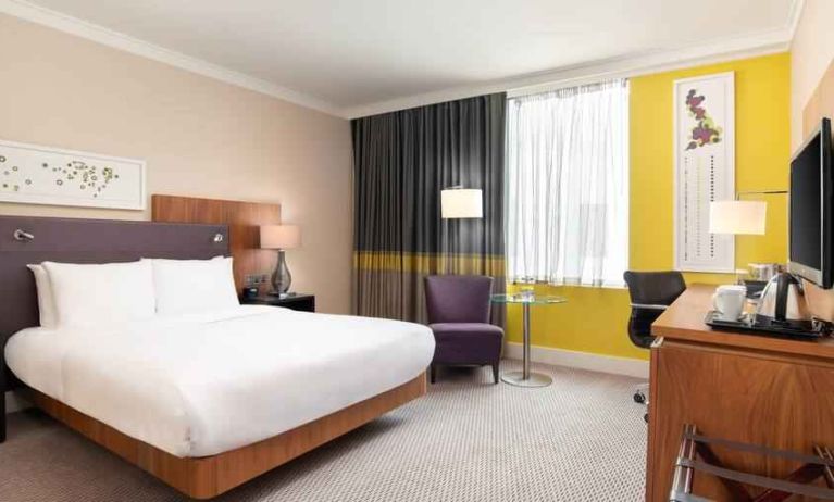 King guestroom with desk and TV screen at the Hilton London Wembley.