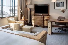 King bedroom with TV screen, sofa and desk at the Hilton London Paddington.