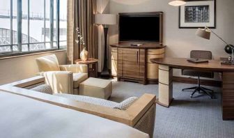 King bedroom with TV screen, sofa and desk at the Hilton London Paddington.