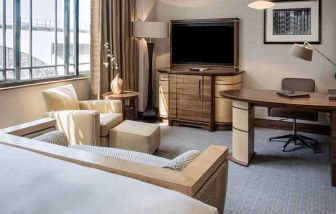 King bedroom with TV screen, sofa and desk at the Hilton London Paddington.