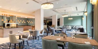 Hotel workspace with tables and chairs at the Hilton London Gatwick Airport.