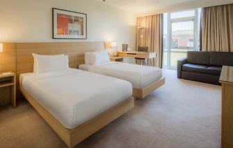 Twin room with sofa, window and desk at the Hilton Northampton.