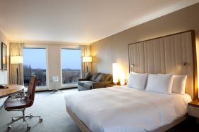 King guestroom with desk and sofa at the Hilton London Heathrow Airport Terminal 5.