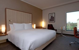 King bedroom with window at the Hilton London Heathrow Airport Terminal 5.