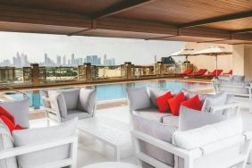 Rooftop pool with seating overlooking a city view at the Hilton Dubai Al Jadaf.