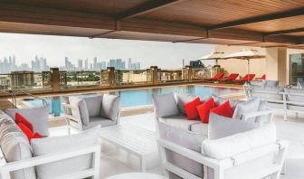 Rooftop pool with seating overlooking a city view at the Hilton Dubai Al Jadaf.