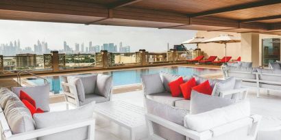 Rooftop pool with seating overlooking a city view at the Hilton Dubai Al Jadaf.