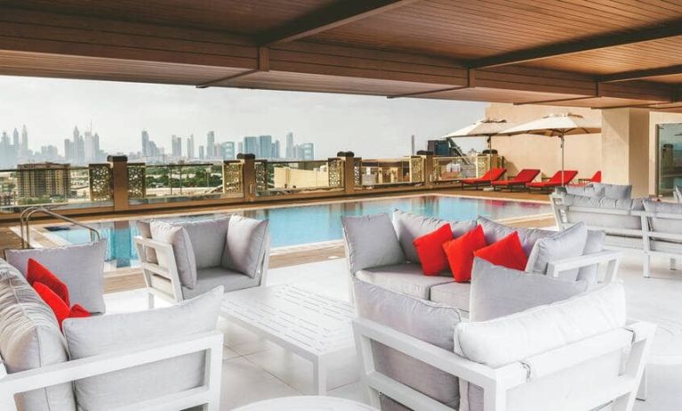 Rooftop pool with seating overlooking a city view at the Hilton Dubai Al Jadaf.