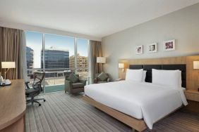 King-sized bed with view of city buildings at the Hilton Garden Inn Dubai Mall of the Emirates.