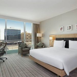 King-sized bed with view of city buildings at the Hilton Garden Inn Dubai Mall of the Emirates.