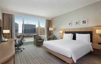 King-sized bed with view of city buildings at the Hilton Garden Inn Dubai Mall of the Emirates.