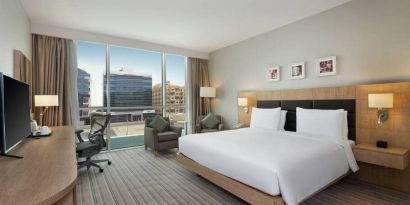 King-sized bed with view of city buildings at the Hilton Garden Inn Dubai Mall of the Emirates.