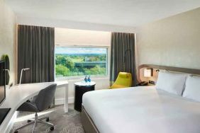 King bedroom with desk and window at the Hilton London Heathrow Airport.