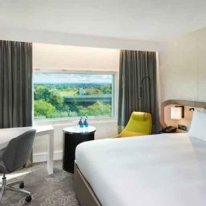 King bedroom with desk and window at the Hilton London Heathrow Airport.