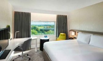 King bedroom with desk and window at the Hilton London Heathrow Airport.