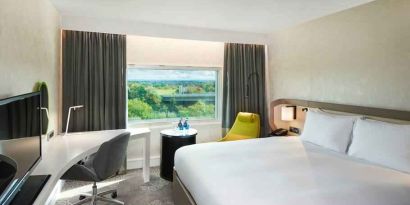 King bedroom with desk and window at the Hilton London Heathrow Airport.