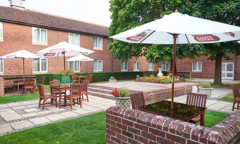 Outdoor patio with chairs, tables and sun umbrellas at the DoubleTree by Hilton Newbury North.