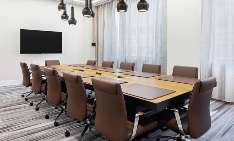 Spacious meeting room with 3 sets of tables and chairs and projector screen at the Canopy by HIlton Atlanta Midtown