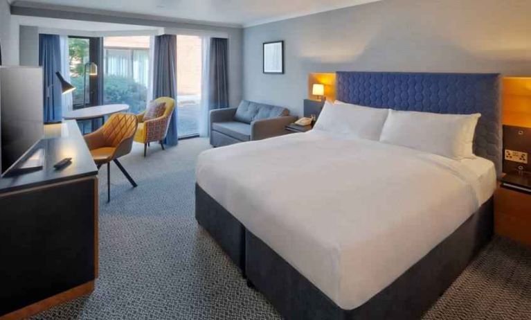 Bright king bedroom with windows and desk at the DoubleTree by Hilton Manchester Airport.