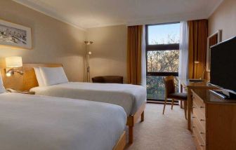 Twin room with desk and TV screen at the Hilton London Kensington.