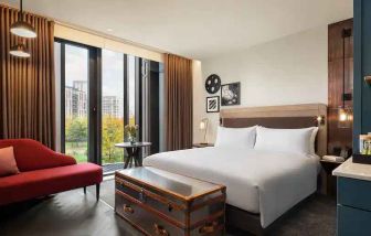 King suite with large window and sofa at the Gantry London, Curio Collection by Hilton.
