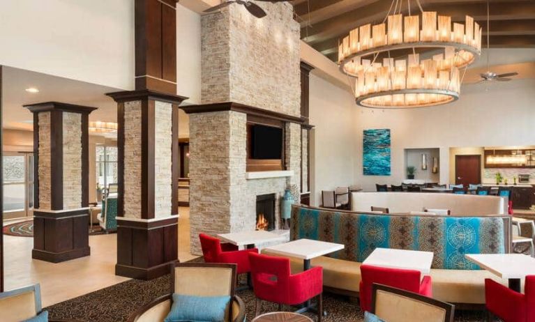 Colorful chairs and booths to eat, socialize or work at. Bright spacious area with large fireplace and chandelier overhead.