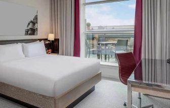 comfortable delux king bed with lots of natural light, work desk, and outside terrace at Hilton London Angel Islington.