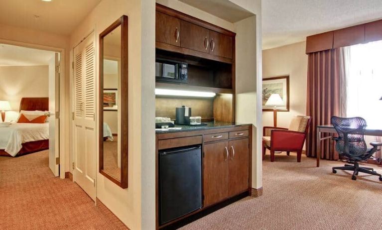 View of entire deluxe suite; king size bed, kitchenette, and area with desk for work at Hilton Garden Inn Calgary Airport.