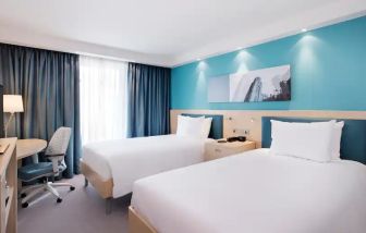 Twin room with TV screen and desk at the Hampton by Hilton Bristol Airport.