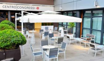 Outdoor terrace with sun umbrellas, chairs and tables at the Hilton Garden Inn Milan North.