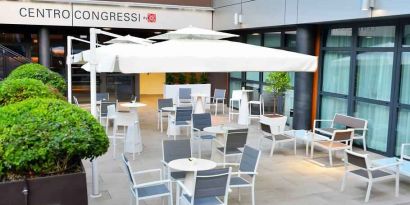 Outdoor terrace with sun umbrellas, chairs and tables at the Hilton Garden Inn Milan North.