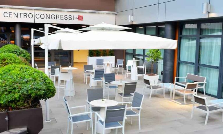 Outdoor terrace with sun umbrellas, chairs and tables at the Hilton Garden Inn Milan North.