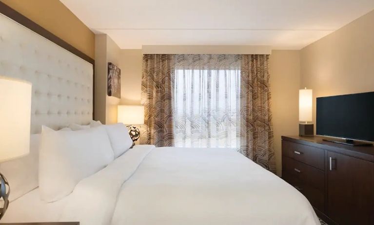 comfortable dim-lit king bedroom with TV at Embassy Suites by Hilton Oklahoma City Downtown Medical Center.