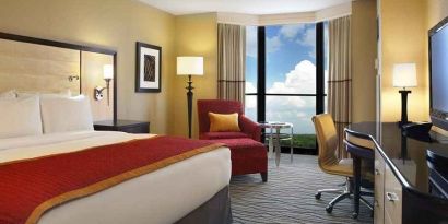 beautiful king suite with TV and work desk with lots of natural light at Hilton Rosemont/Chicago O'Hare.