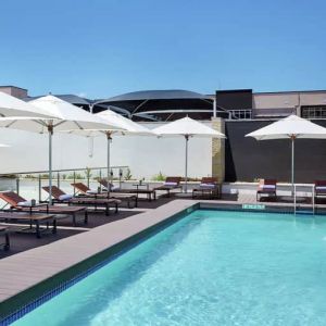 Narrow rectangular pool with fountains coming out of side wall, abundant lounge chairs for sunbathing.