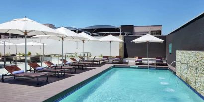 Narrow rectangular pool with fountains coming out of side wall, abundant lounge chairs for sunbathing.