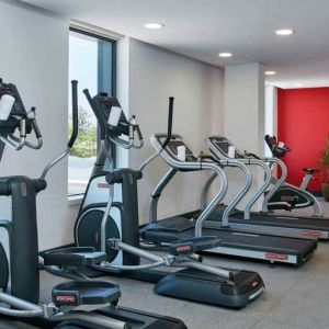 Ellipticals, treadmills, and space for free weights in hotel exercise room.