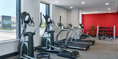 Ellipticals, treadmills, and space for free weights in hotel exercise room.