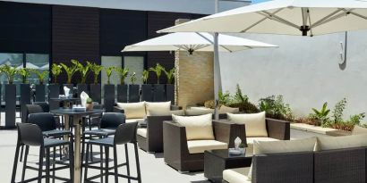 Round cocktail tables with seating for 4 or cabana lounge areas for seating for 4-6 people on outside hotel patio.