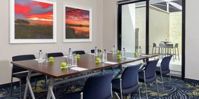 Small meeting room with rectangular table and seating for 8 guests.