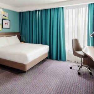 King guestroom with TV screen and desk at the Hampton by Hilton Belfast City Centre.