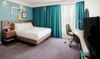 King guestroom with TV screen and desk at the Hampton by Hilton Belfast City Centre.