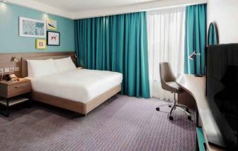 King guestroom with TV screen and desk at the Hampton by Hilton Belfast City Centre.