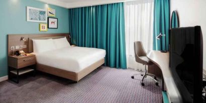 King guestroom with TV screen and desk at the Hampton by Hilton Belfast City Centre.