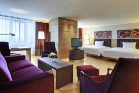 Spacious twin room with beds, desk, TV screen and sofa at the Hilton Mainz.