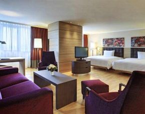 Spacious twin room with beds, desk, TV screen and sofa at the Hilton Mainz.